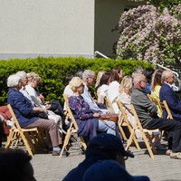 2.	Zdjęcie przedstawia ludzi siedzących na krzesłach, skierowanych w stronę sceny.